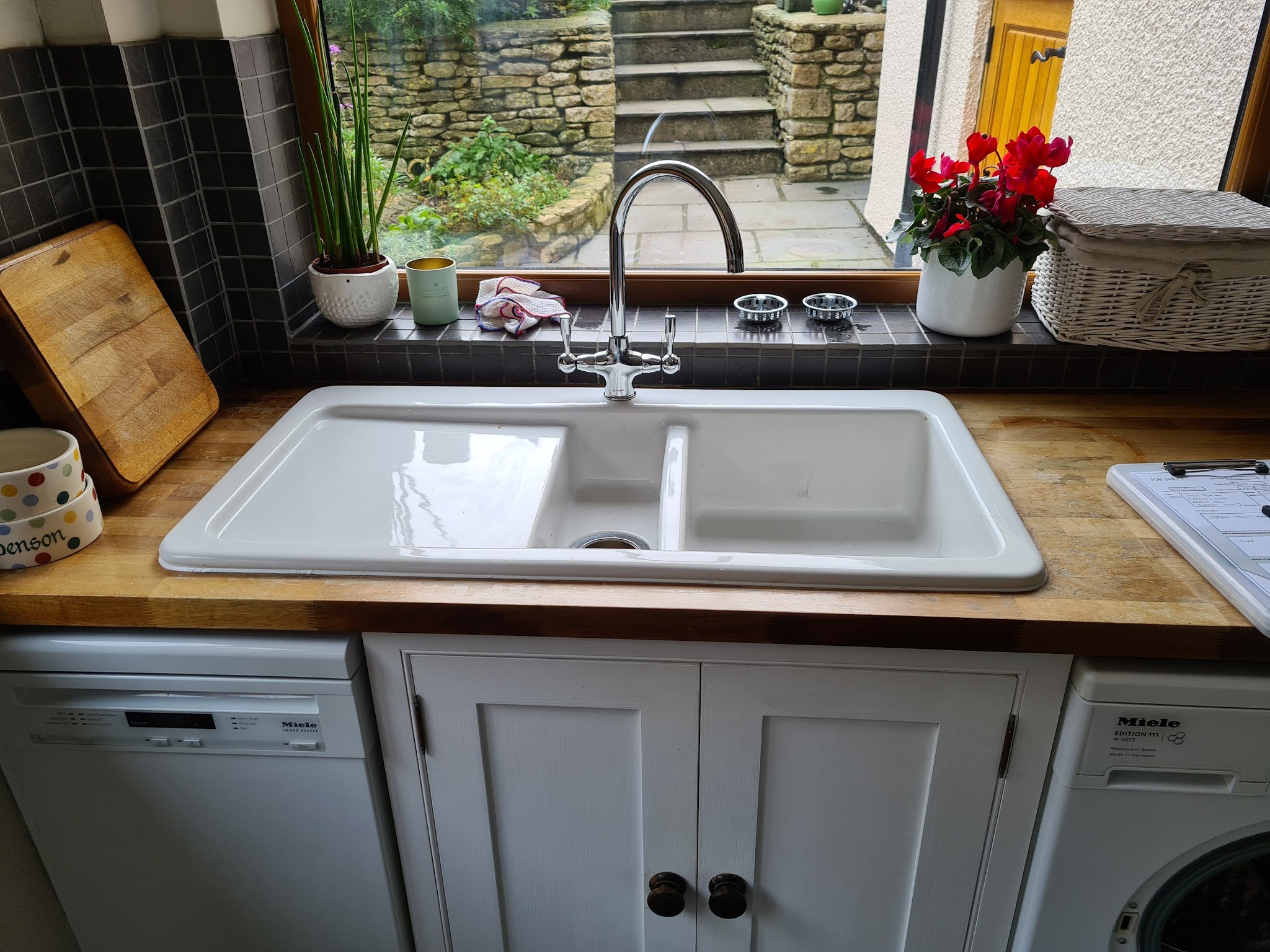 A white double ceramic kitchen sink with a mixer tap on a wooden worktop
